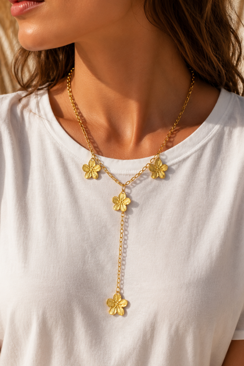 Gouden Aloha flower lange ketting van Fencyjewels gedragen door een model, met meerdere bloemdetails en een lange hanger.