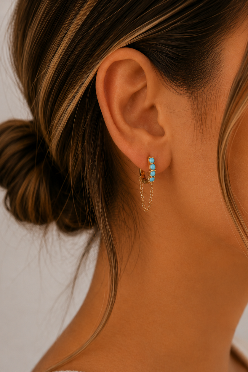 Model draagt de gouden Amalfi glow oorbellen van Fencyjewels met turquoise details en een verfijnd hangertje.