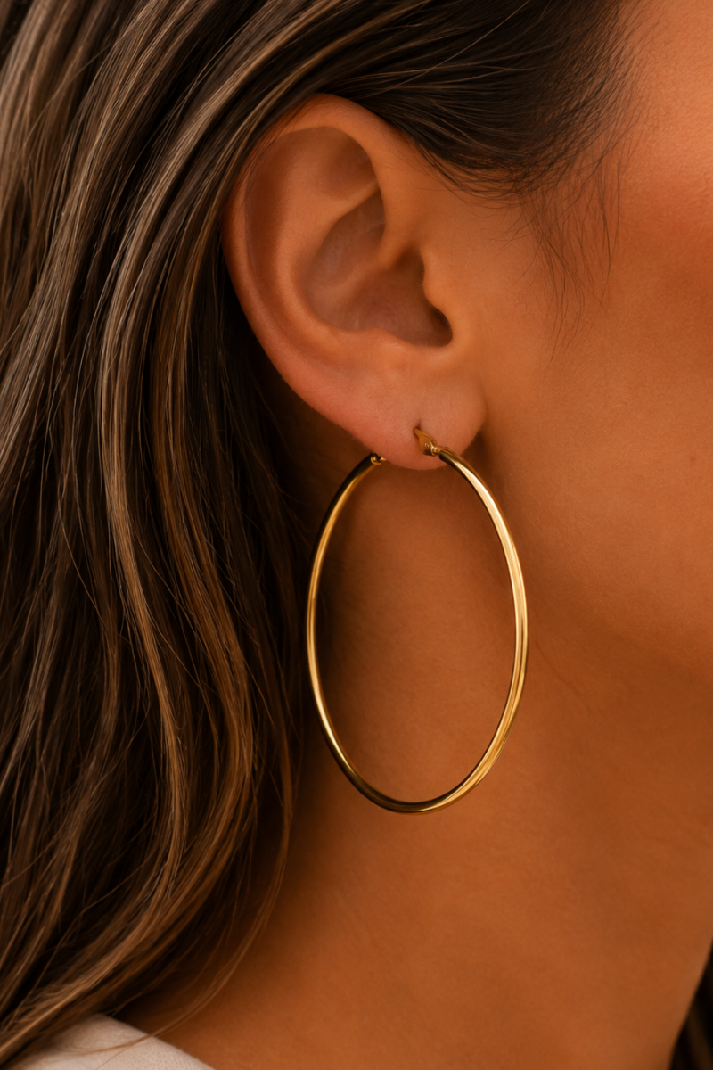 Gouden Basic hoops 6cm van Fencyjewels gedragen in het oor, grote minimalistische oorringen met een tijdloos design.