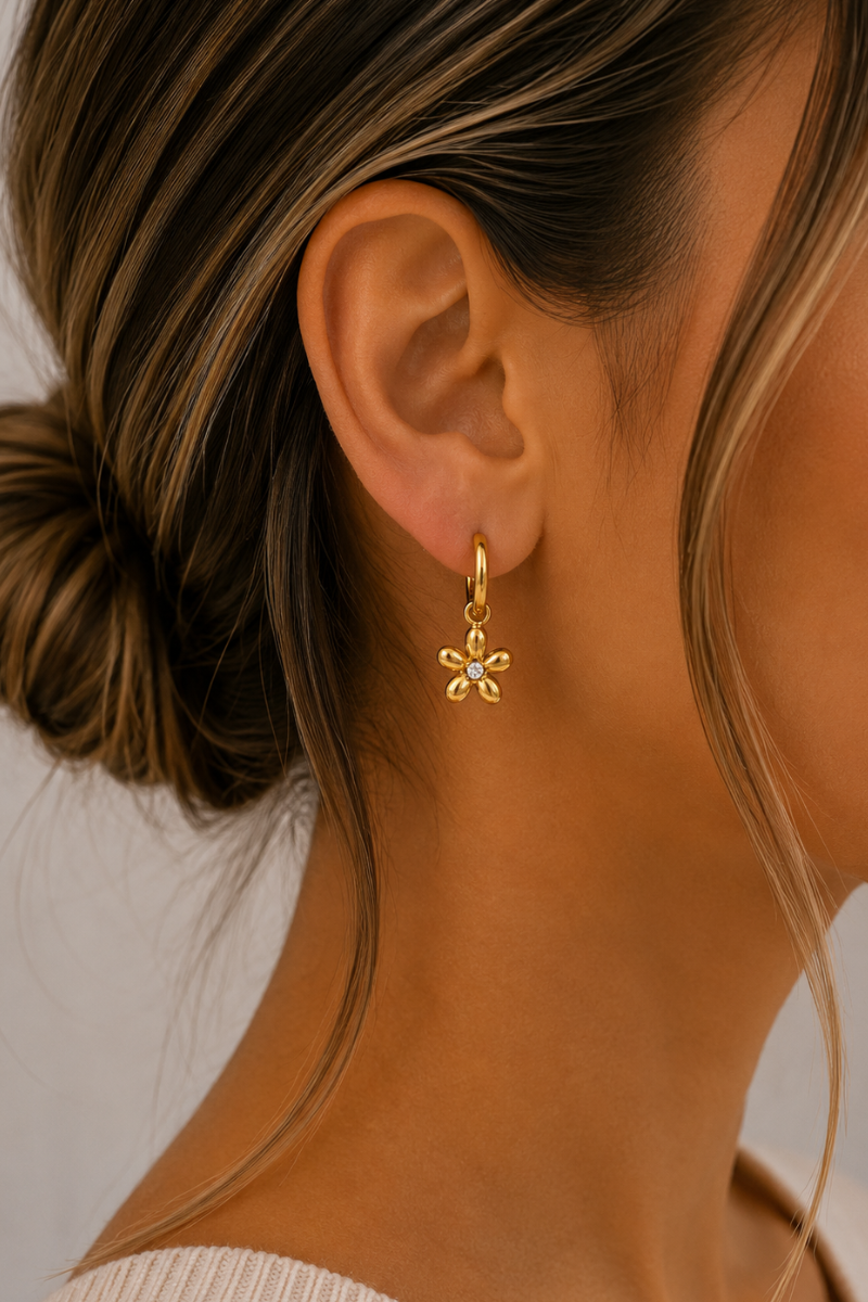 Model draagt de gouden Bloemetjes oorbellen van Fencyjewels met kleine hoops en verfijnde bloemenhangertjes.