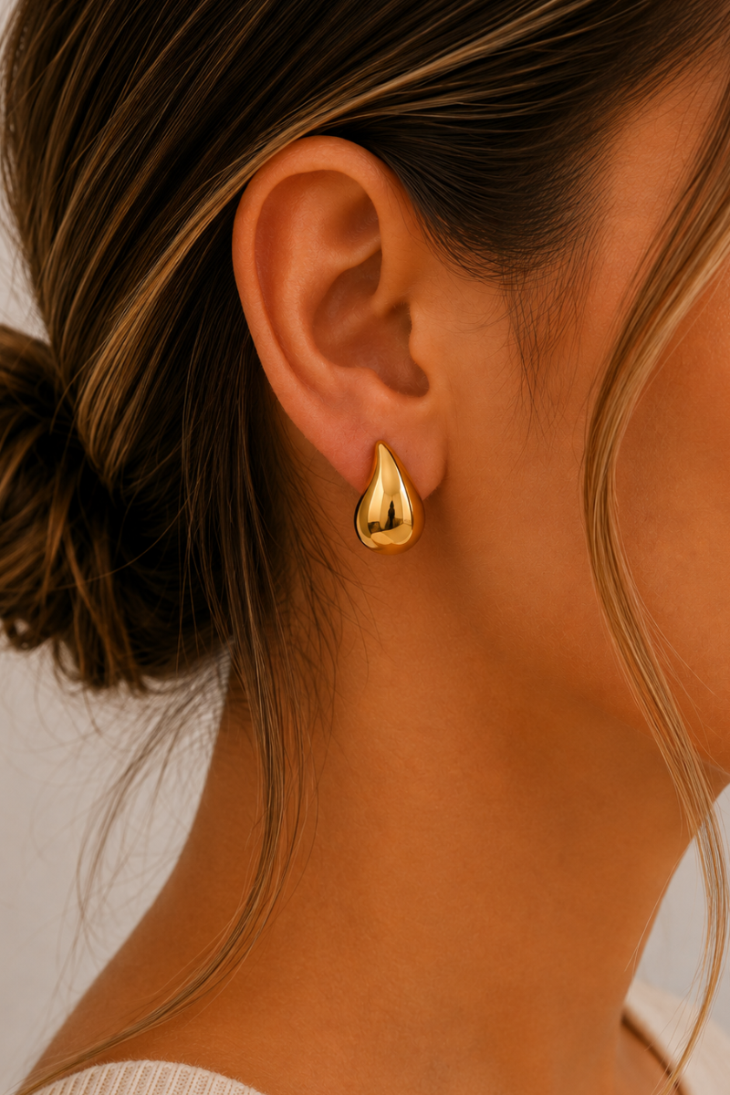 Model draagt de gouden Druppel oorbellen van Fencyjewels met een elegant en modern druppelvormig design.