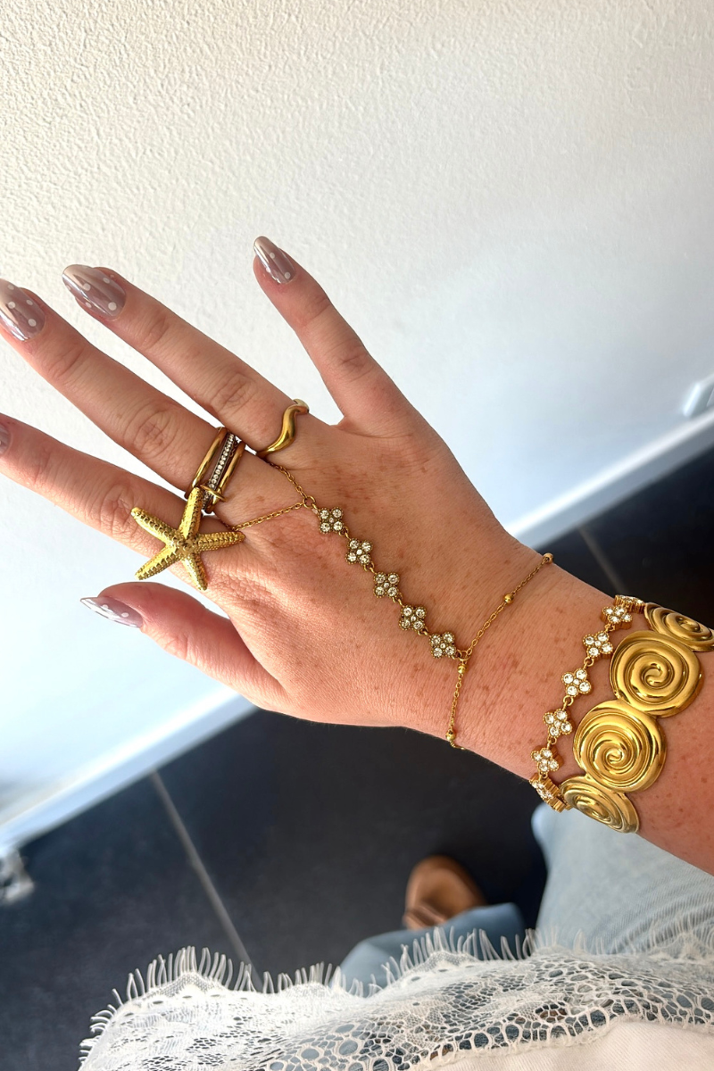 Flower armband van Fencyjewels gedragen om de pols met goudkleurige bloemen en sprankelende details.