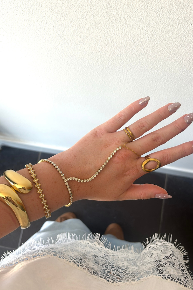Gouden Flower bangle van Fencyjewels gedragen om de pols met verfijnde bloemdetails en steentjes.