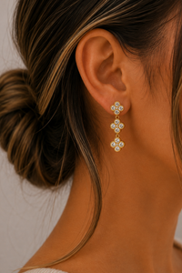Model draagt de gouden Flower oorbellen van Fencyjewels met meerdere verfijnde bloemen en sprankelende steentjes.
