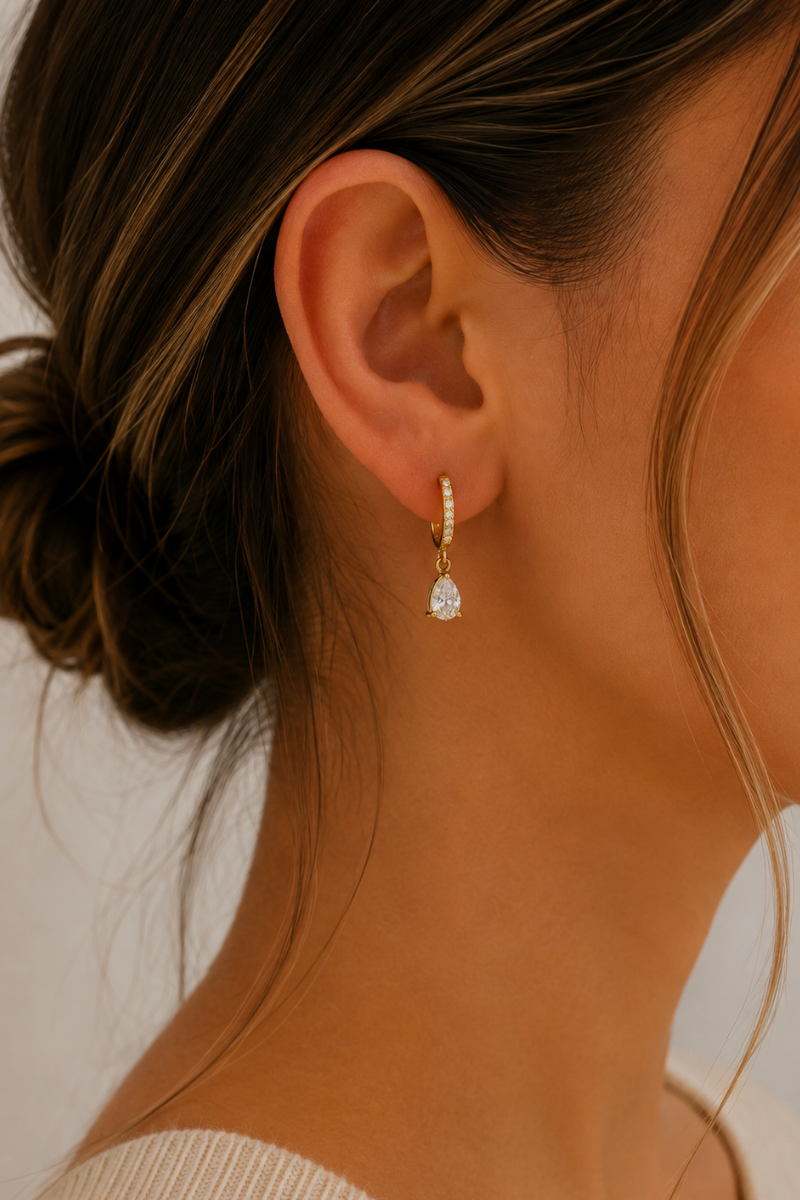 Model draagt de gouden Paris oorbellen van Fencyjewels met een klein elegant hangertje en verfijnd design.