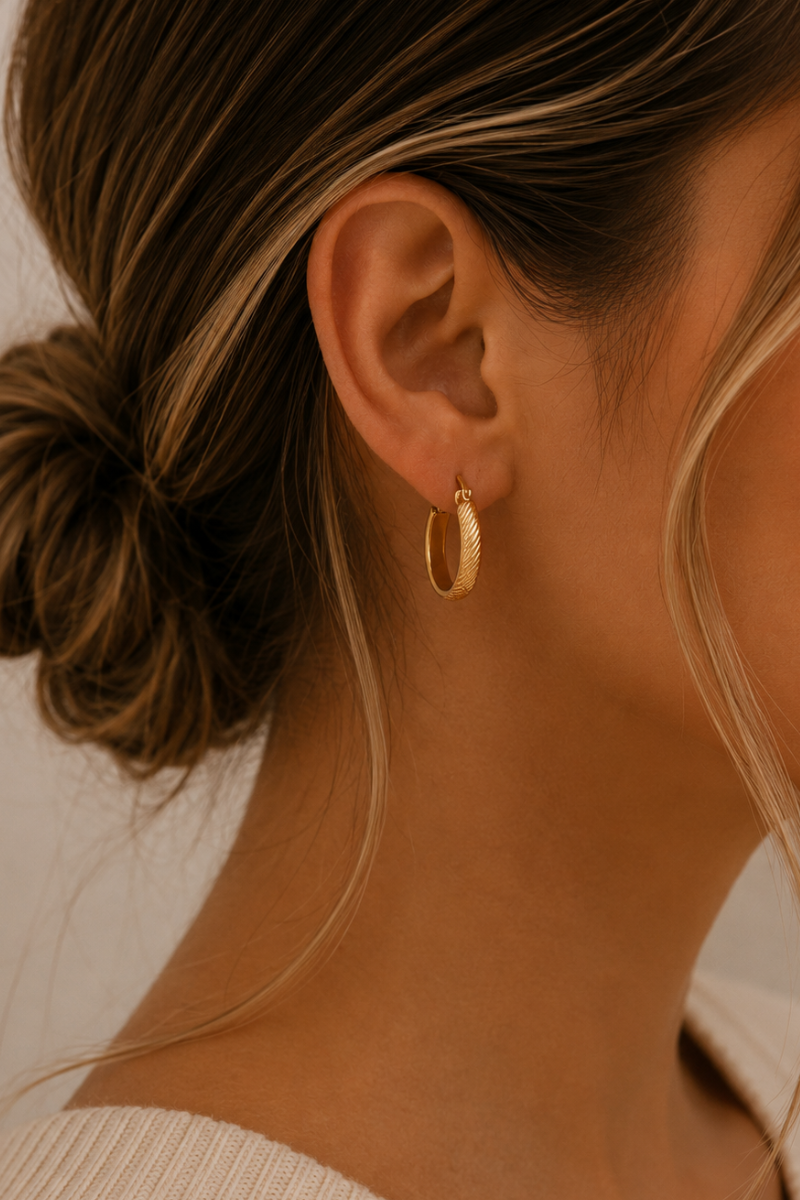 Model draagt de gouden Ribbed hoops van Fencyjewels met een subtiele geribbelde structuur en ronde vorm.