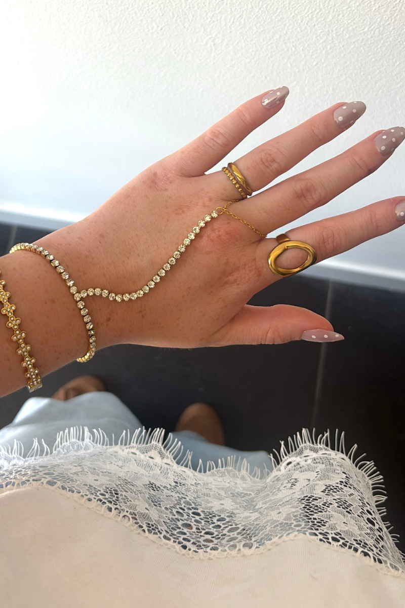 Gouden Sparkle handchain van Fencyjewels gedragen om de hand met een verfijnd kettinkje tussen pols en vinger.