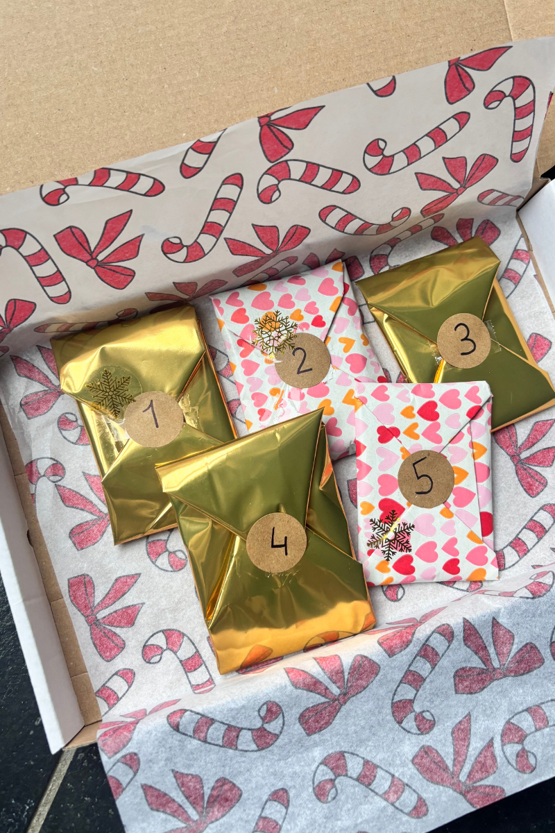 Fencyjewels advent cadeaupakket met vijf luxe ingepakte sieraden in gouden en hartjespapier, feestelijk verpakt in kerstdoos — handgemaakt en verzonden vanuit Nederland en België.