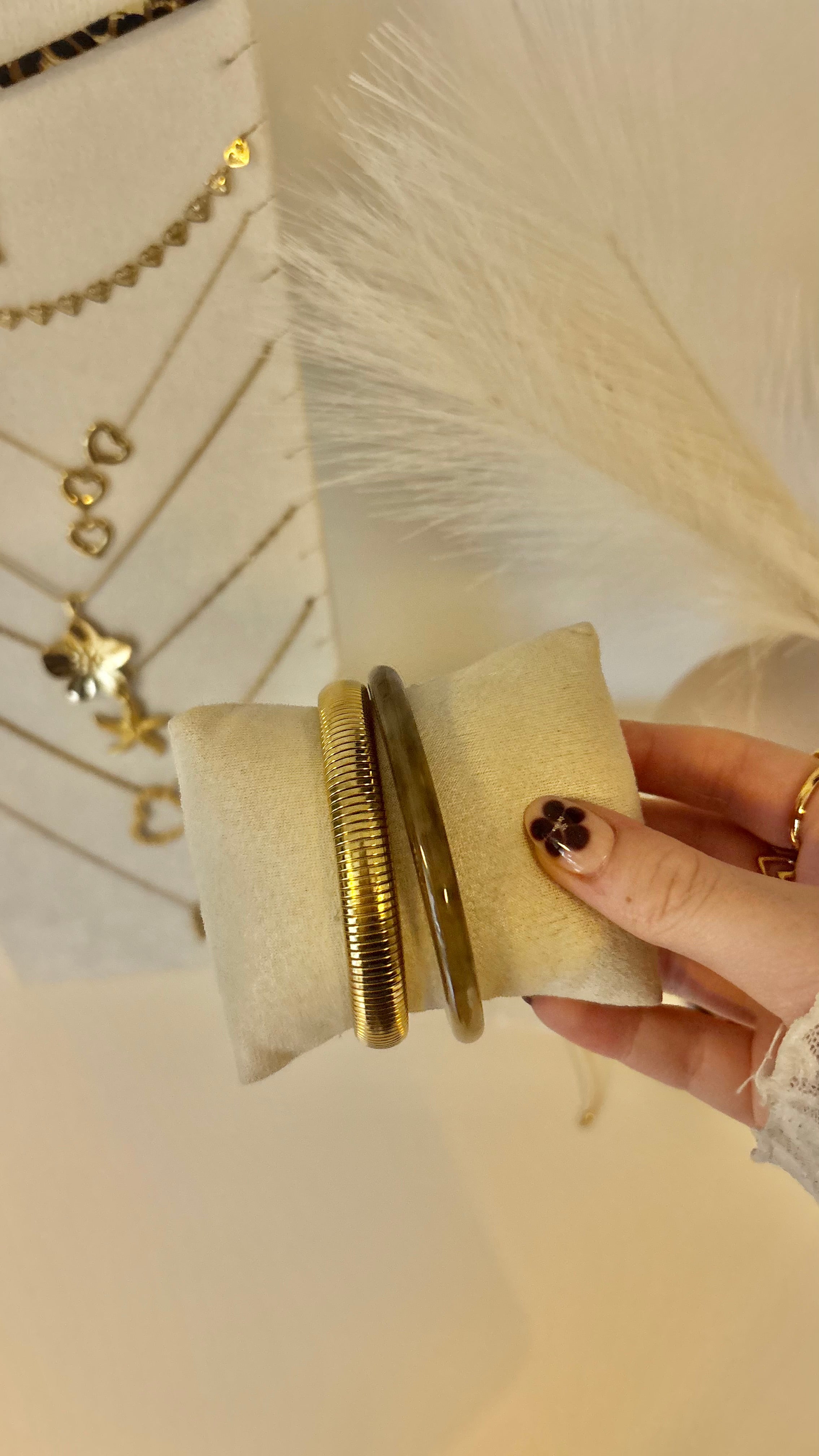 Bruine bangle armband van Fencyjewels getoond op sieradenkussen in de hand. Stijlvolle armband met warme tinten, perfect te combineren met gouden sieraden.