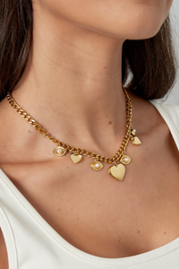 Gouden eye of love ketting van Fencyjewels gedragen op een witte top voor een trendy layered look.