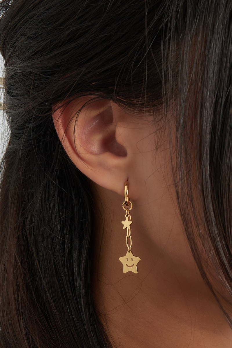 Lifestyle detail van de gouden happy star oorbellen van Fencyjewels voor een speelse look.