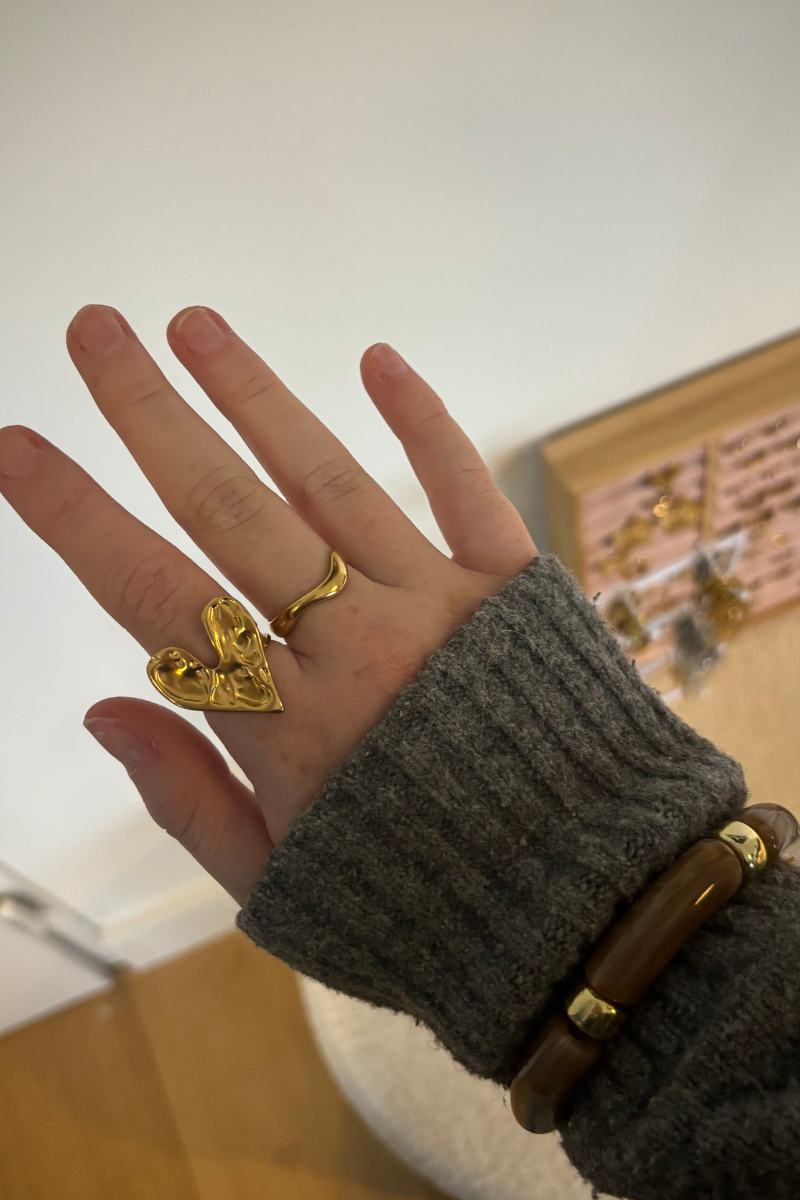 Foto van de gouden love ring gedragen aan de hand, minimalistische ringstack.