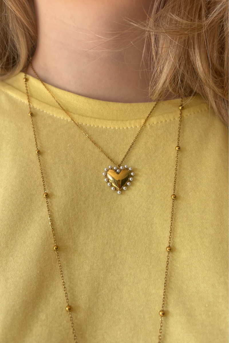 Fency pearl ketting van Fencyjewels close-up gedragen om de hals. Gouden ketting met hartje en pareldetails voor een stijlvolle en zachte uitstraling.