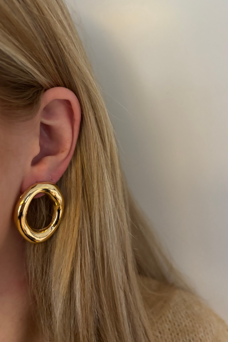 Sfeerfoto van de gouden round circle oorbellen gedragen in het oor, een tijdloze toevoeging aan je ear-party.