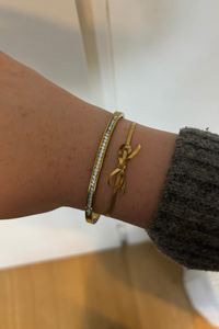 Sfeerfoto van de gouden strikjes armband om de pols, gecombineerd met andere Fencyjewels sieraden.