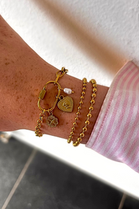 Gouden armbanden van Fencyjewels met hart-, klavertjevier- en parelbedel, gecombineerd met kralenarmbanden voor een elegante look.