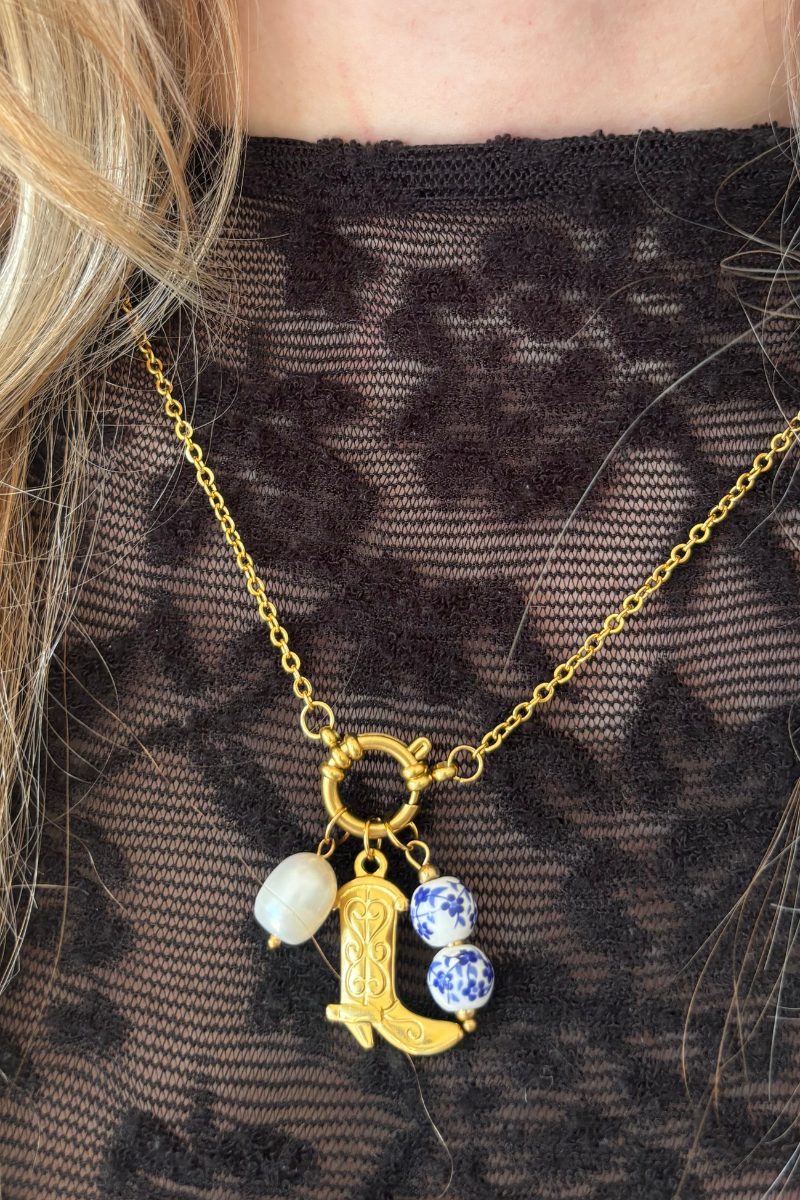 Fencyjewels gouden ketting met cowboylaars bedel, parel en blauw-wit keramieken kralen – unieke bedelketting voor dames met stijlvolle western look.