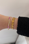 Fencyjewels gouden bloemenarmband gecombineerd met roze en witte kralenarmband – elegante dames sieraden met een zomerse, stijlvolle uitstraling.