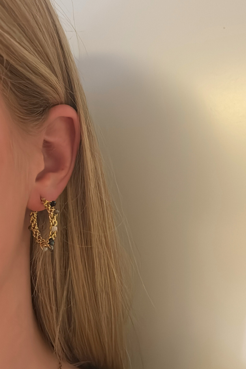 Gouden oorbel met zwarte, grijze en witte kralen van Fencyjewels, gedragen aan het oor voor een stijlvolle en luxe look.