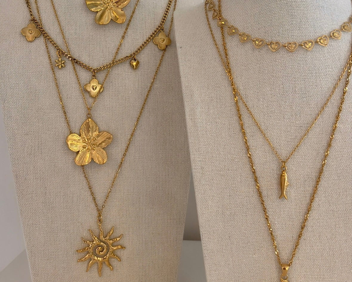 Fencyjewels gouden sieraden set met zeester ketting en verschillende ringen. Hand met stijlvolle gold plated ringen in hart-, golf- en zonvorm voor een chique zomerse look.