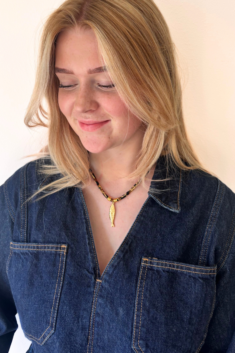 Fencyjewels gouden vis ketting – korte damesketting met goudkleurige fish pendant en zwarte kralen, zomerse en trendy look, perfect voor een beachy outfit.