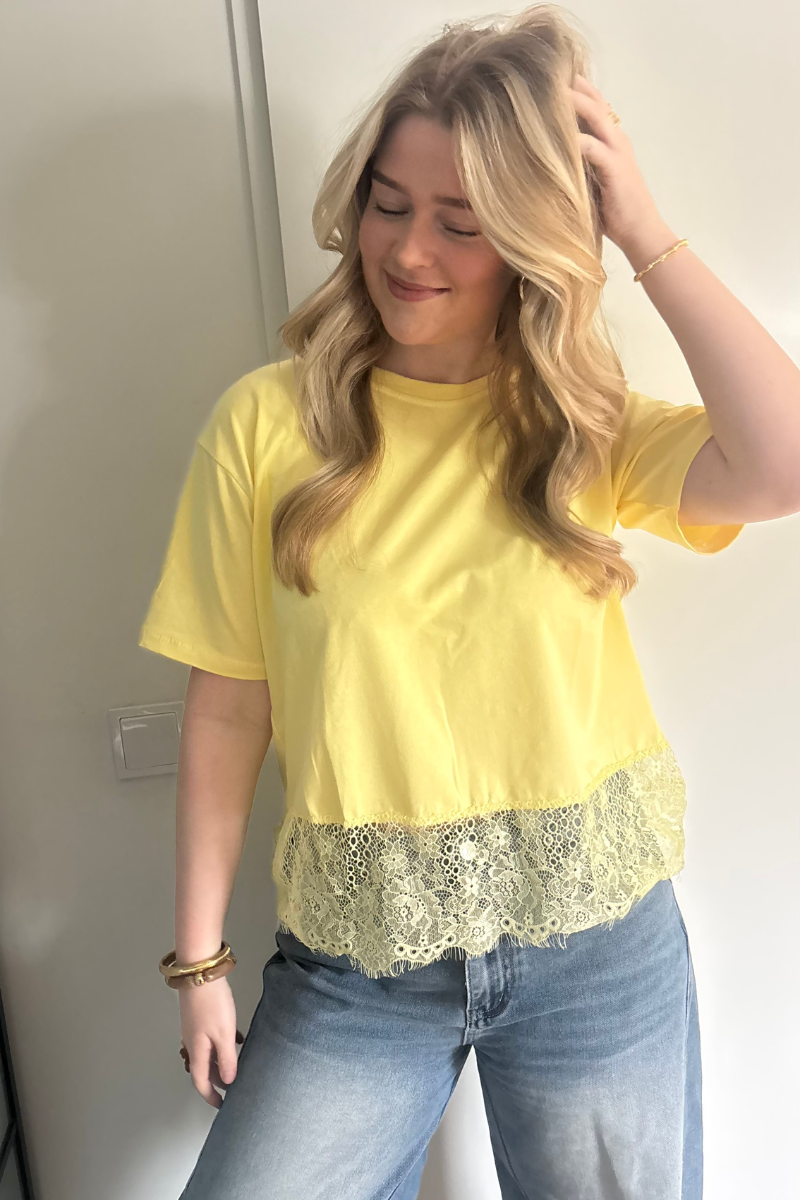 Gele kantentop van Fencyjewels gedragen door model. Luchtige top met kanten detail en zachte stof, ideaal voor een zomerse en vrolijke outfit.