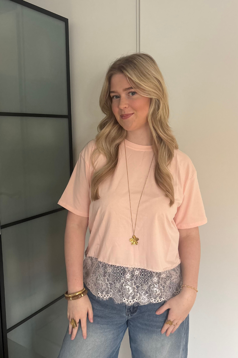 Lichtroze kantentop van Fencyjewels gedragen door model. Zachte top met kanten onderrand en comfortabele pasvorm, perfect voor een vrouwelijke en elegante look.