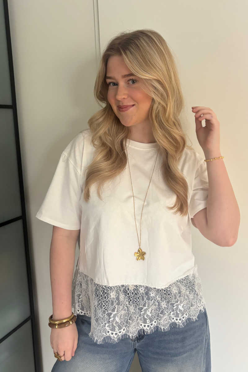 Witte kantentop van Fencyjewels gedragen door model. Stijlvolle top met kanten detail en luchtige stof, ideaal voor een frisse en tijdloze outfit.