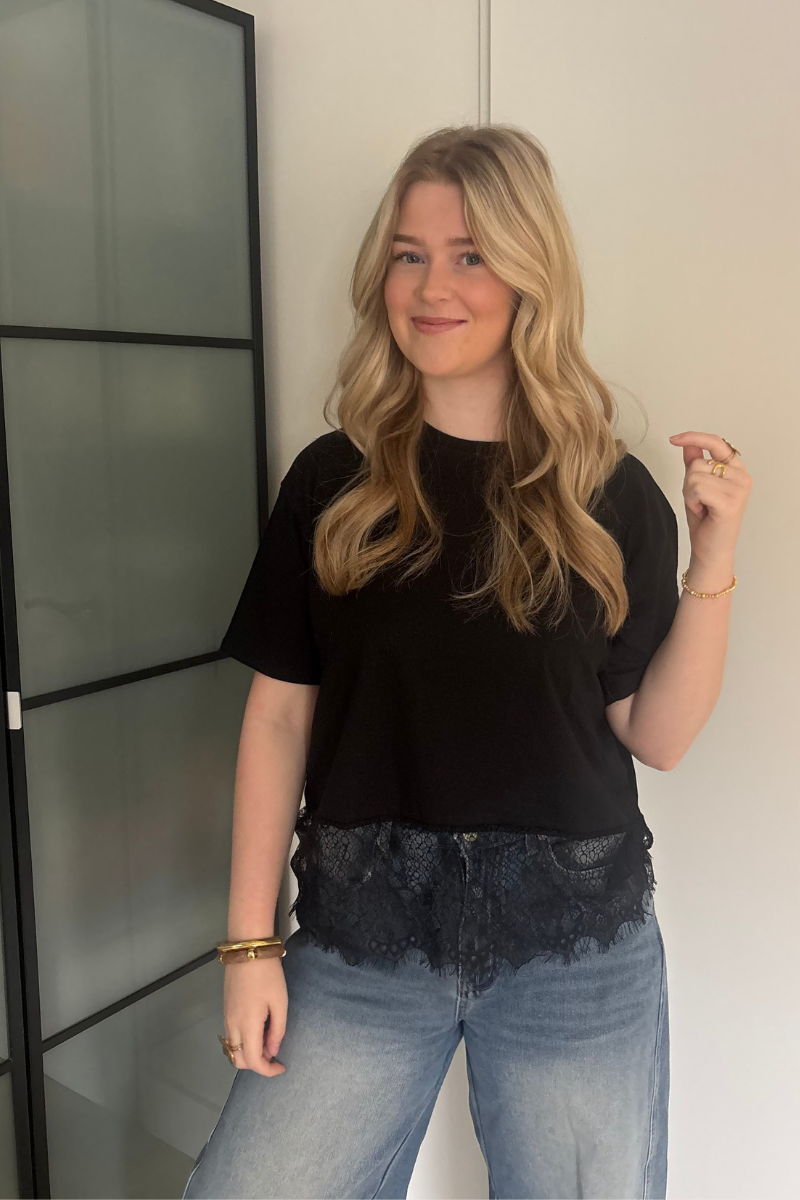 Zwarte kantentop van Fencyjewels gedragen door model. Elegante top met kanten afwerking en comfortabele fit, perfect voor een classy look.