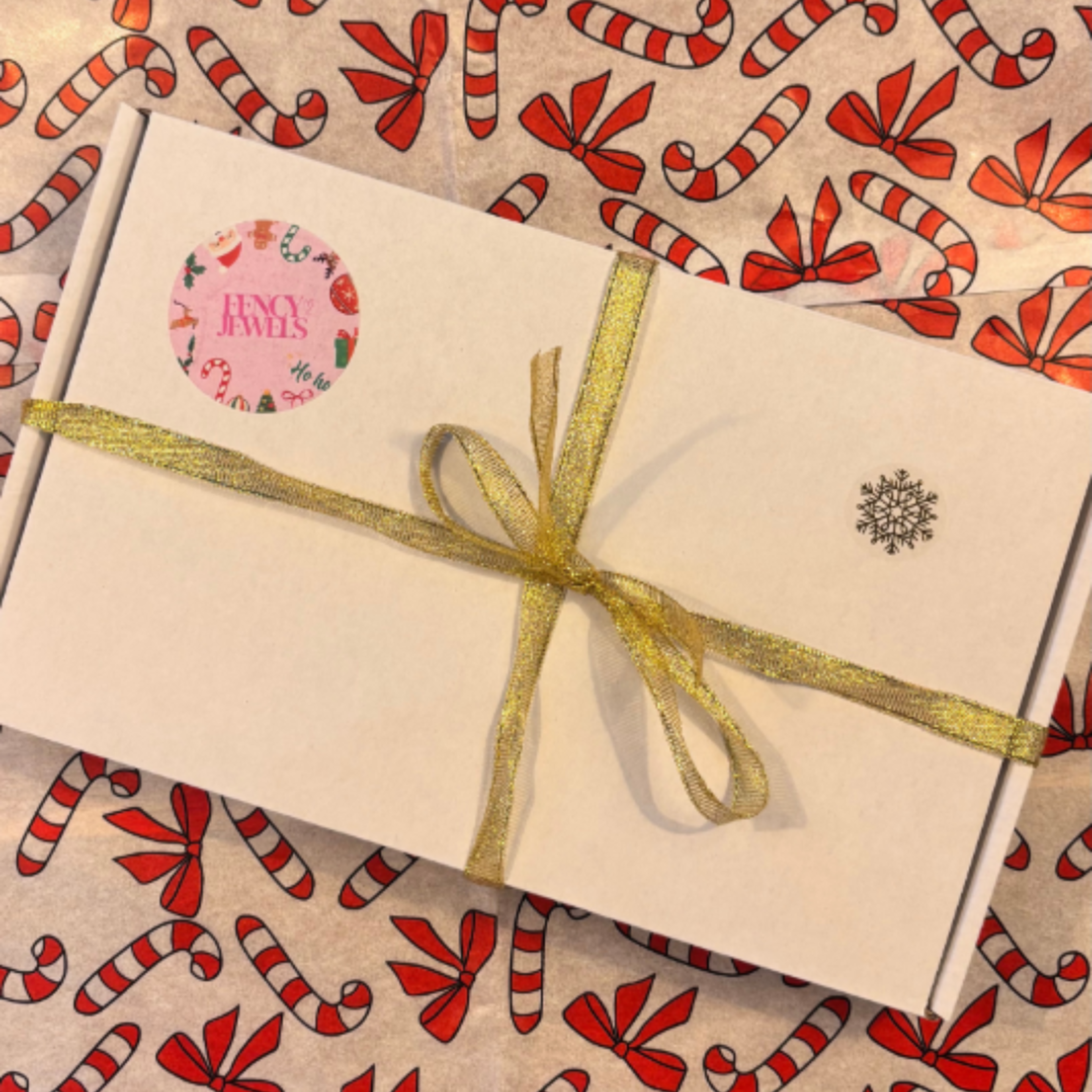 Fencyjewels kerstcadeauverpakking met gouden lint en feestelijke candy cane achtergrond, luxe sieradendoosje voor cadeau’s uit Nederland en België.