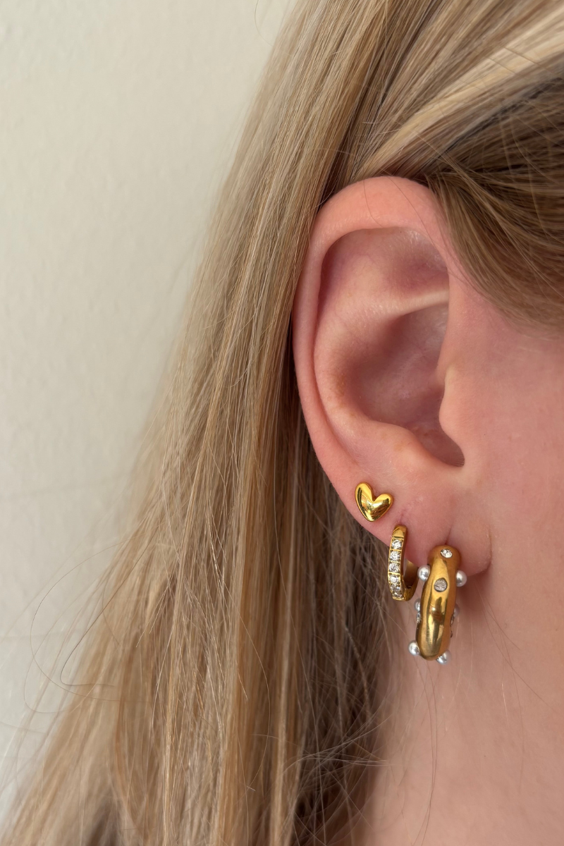 Small heart studs van Fencyjewels gedragen in het oor. Subtiele gouden oorbellen met hartje, ideaal voor een minimalistische en vrouwelijke look.