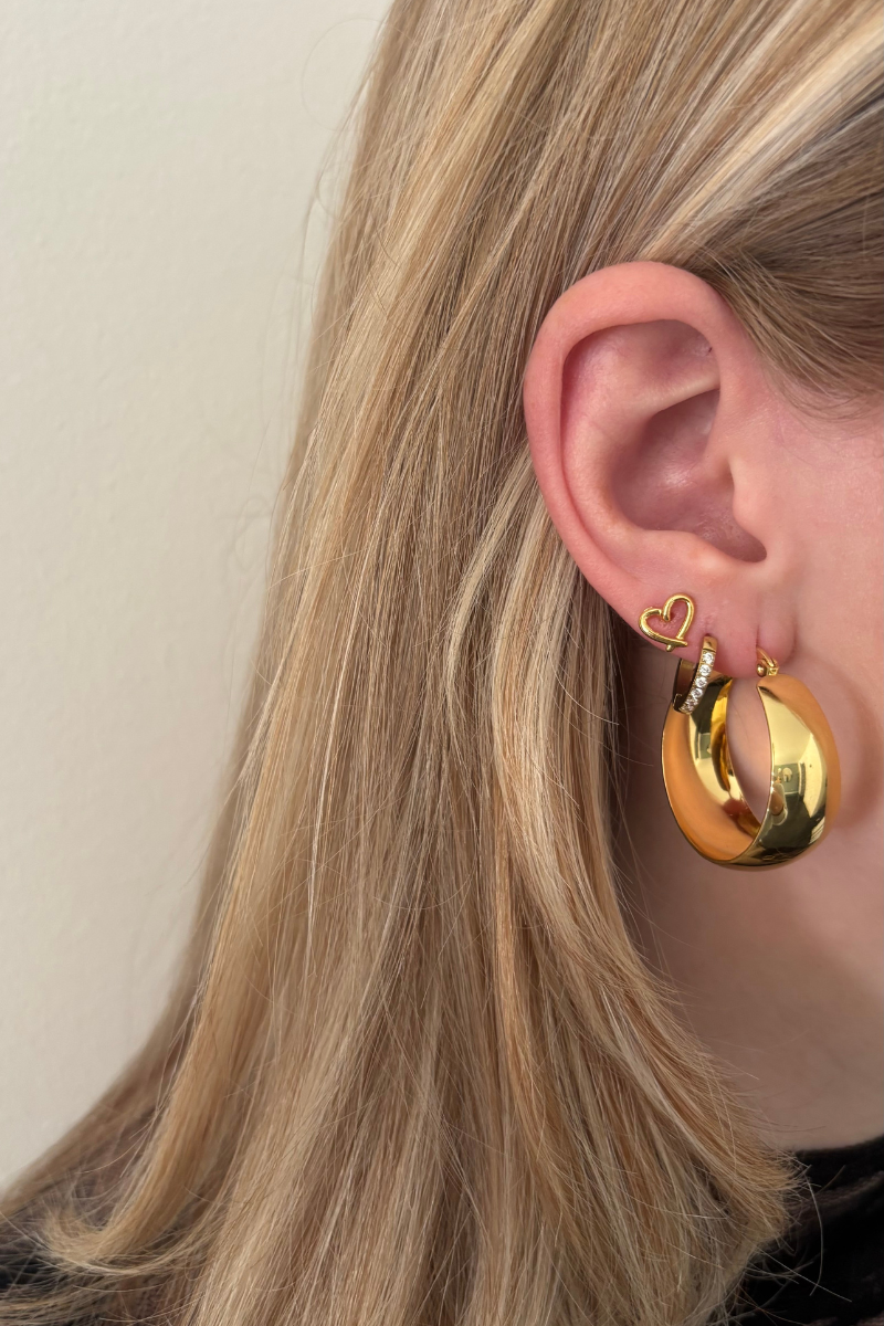 Small open heart studs van Fencyjewels gedragen in het oor. Subtiele gouden oorbellen met open hartje, ideaal voor een elegante en minimalistische look.